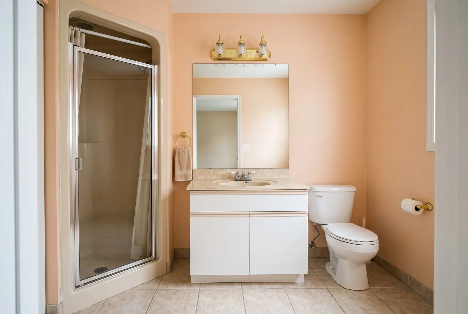 A 1990s hall bathroom with a one-piece shower stall, a framed glass door and a cultured marble vanity top