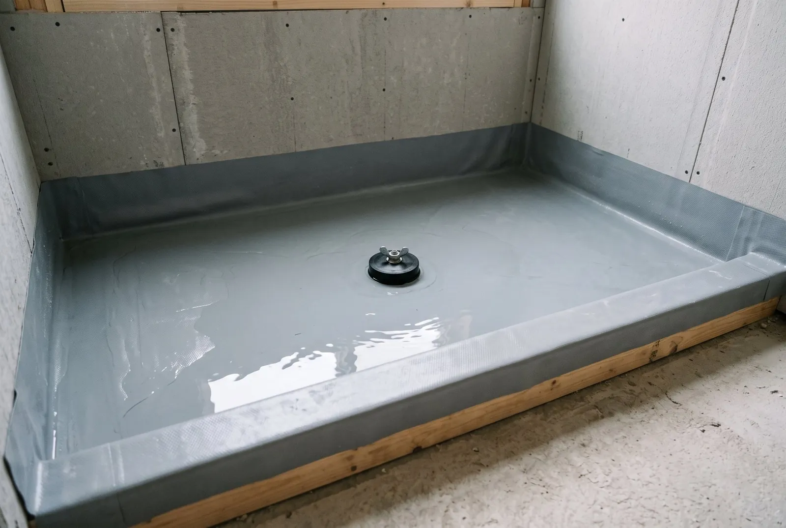 A shower floor liner holding still water with the drain plugged, before any tile