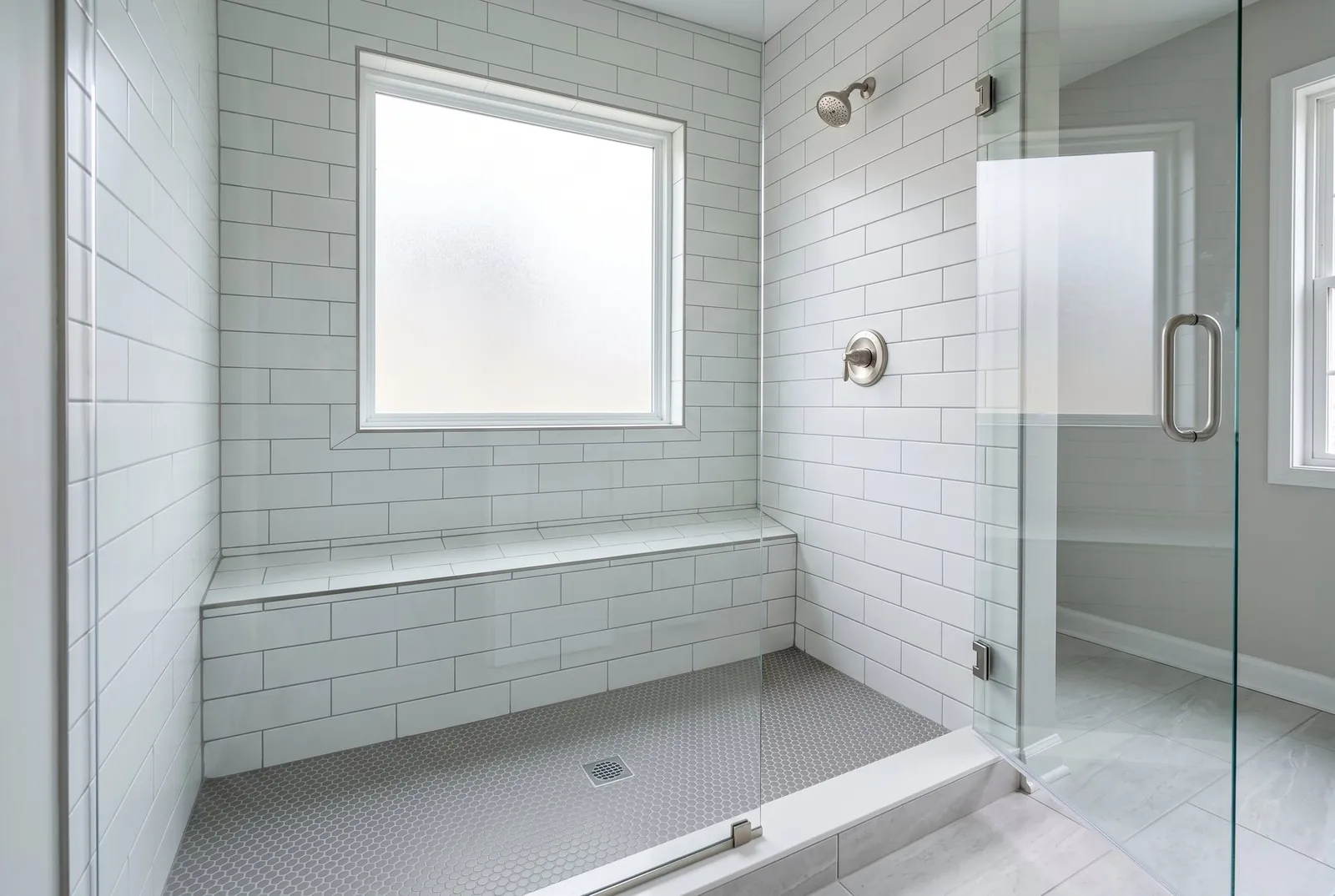 A tiled shower with a frosted window in its back wall