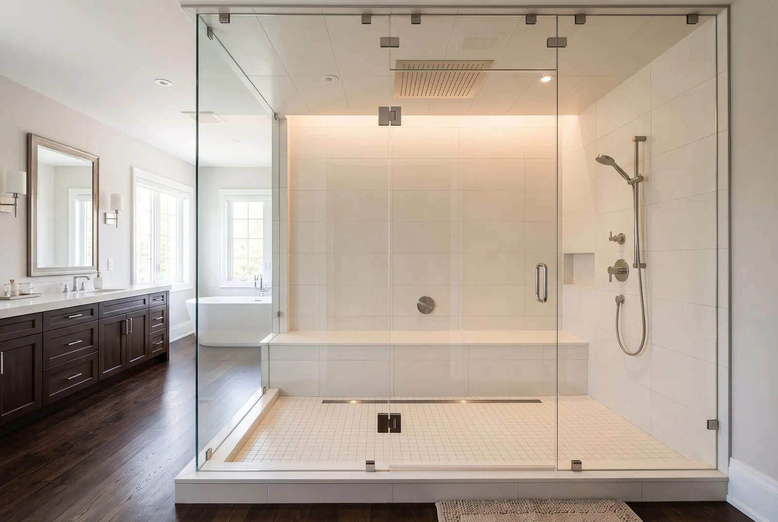 A large shower enclosed in clear glass to the ceiling, with a long built-in bench and a rain head